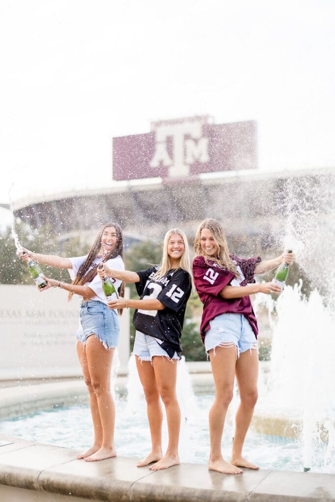 Adeline, her sister, and best friend popping champagne in celebration captured by Texas A&M Photographer.