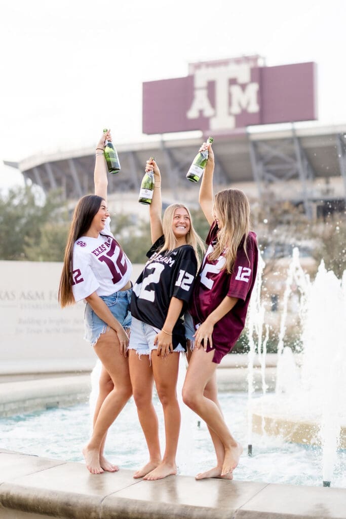 Adeline, her sister, and best friend popping champagne in celebration during her Texas A&M graduation session