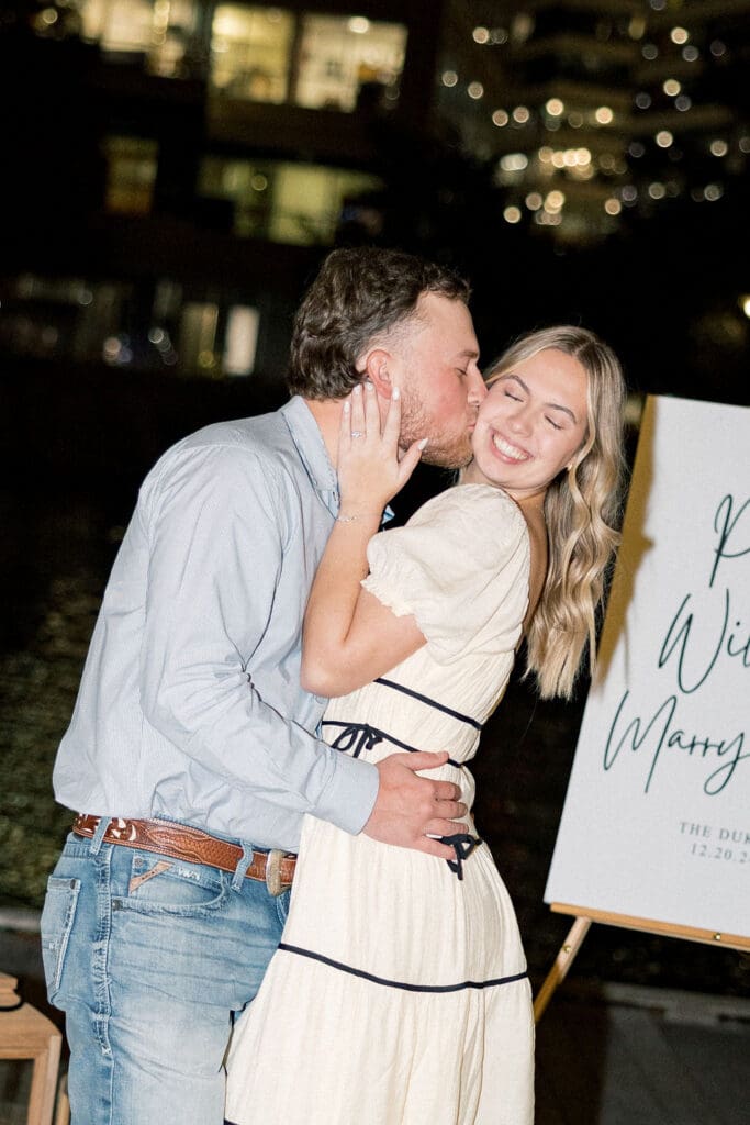 Couple sharing an intimate moment during surprise proposal at Hughes Landing in The Woodlands