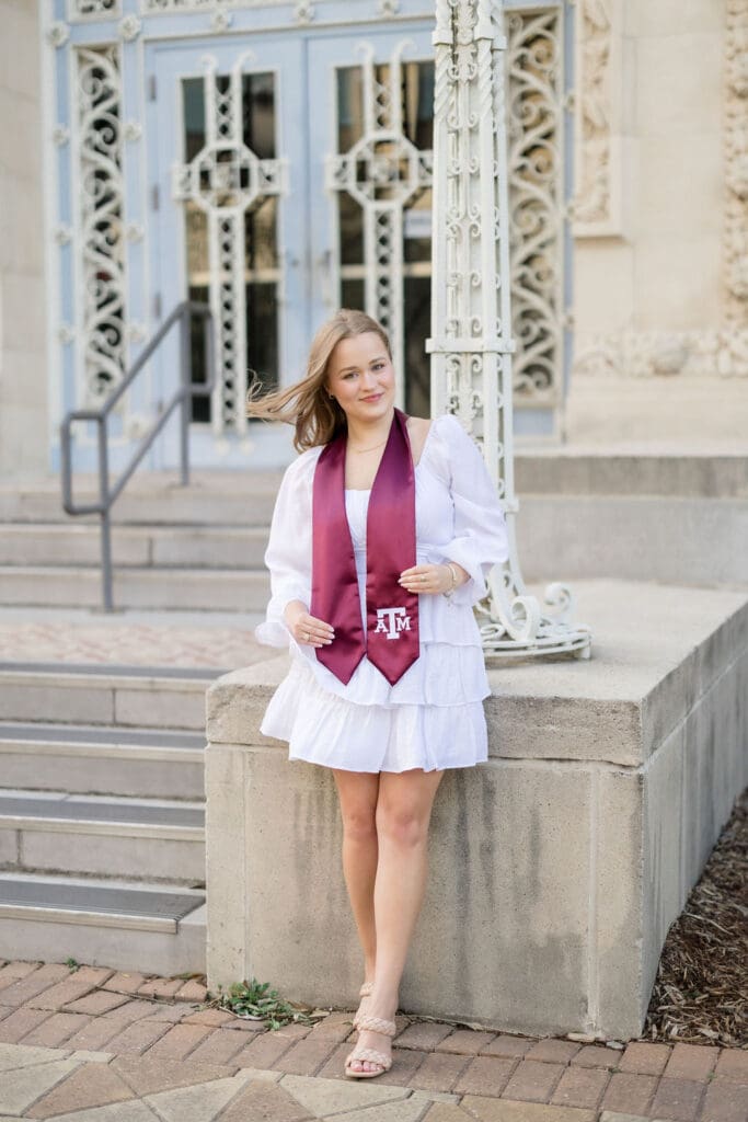 TAMU senior photos at Scoates Hall with Grace standing in front of the blue doors in a white dress