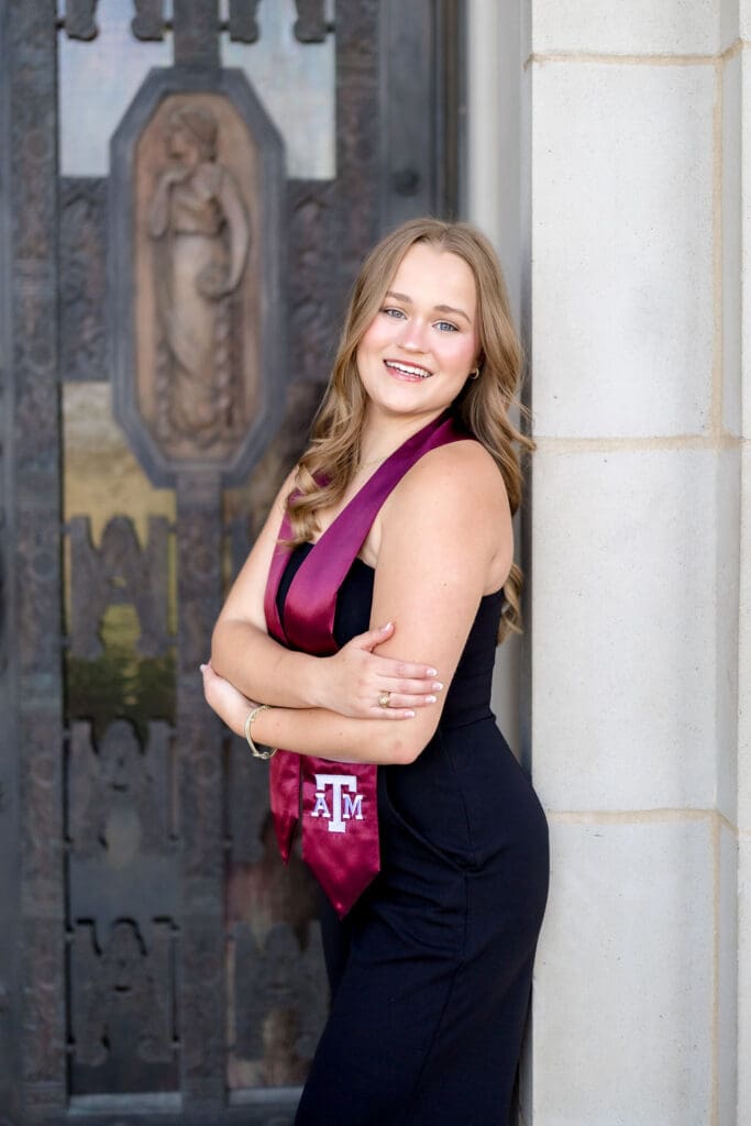 TAMU senior photos of Grace posing at the Texas A&M Administration Building in her graduation cap and gown