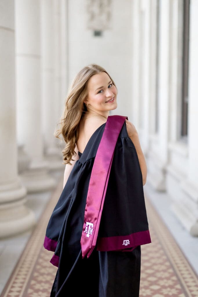TAMU senior photos of Grace posing at the Texas A&M Administration Building in her graduation cap and gown