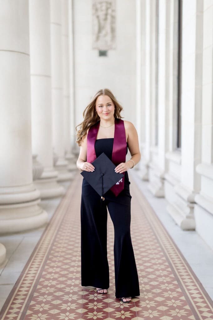 TAMU senior photos of Grace posing at the Texas A&M Administration Building in her graduation cap and gown