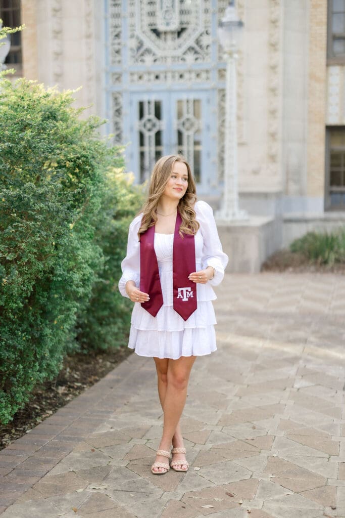 TAMU senior photos at Scoates Hall with Grace standing in front of the blue doors in a white dress