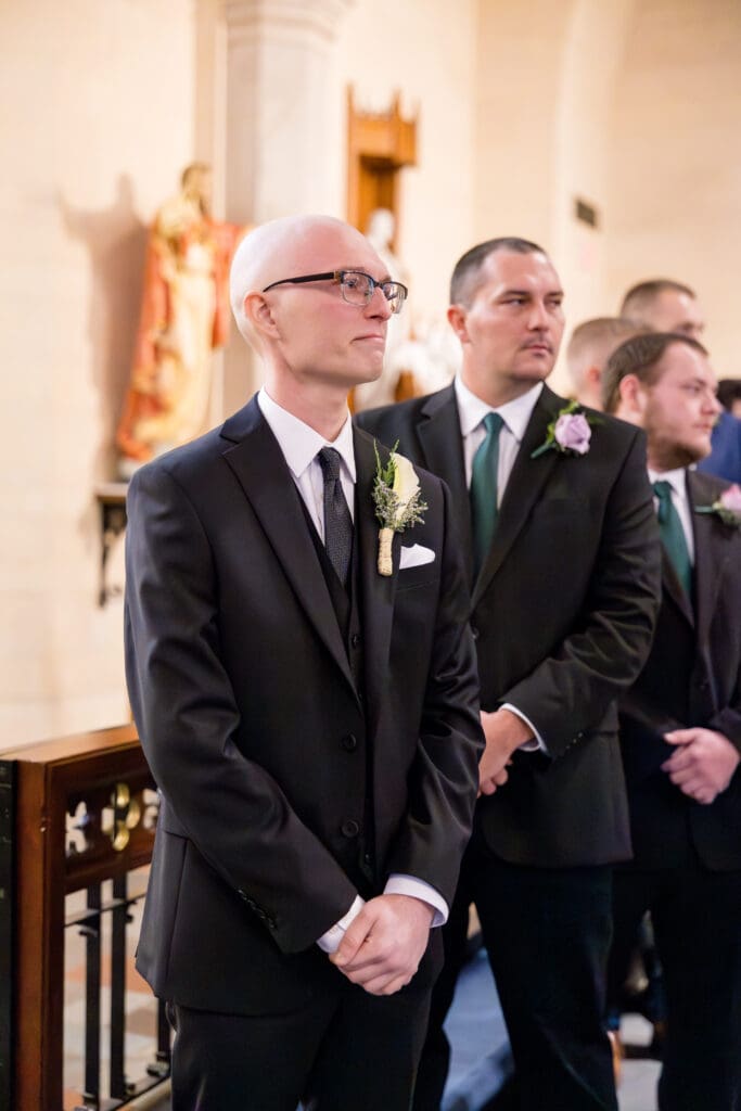 Groom Hunter waiting at altar during Catholic wedding ceremony in Texas