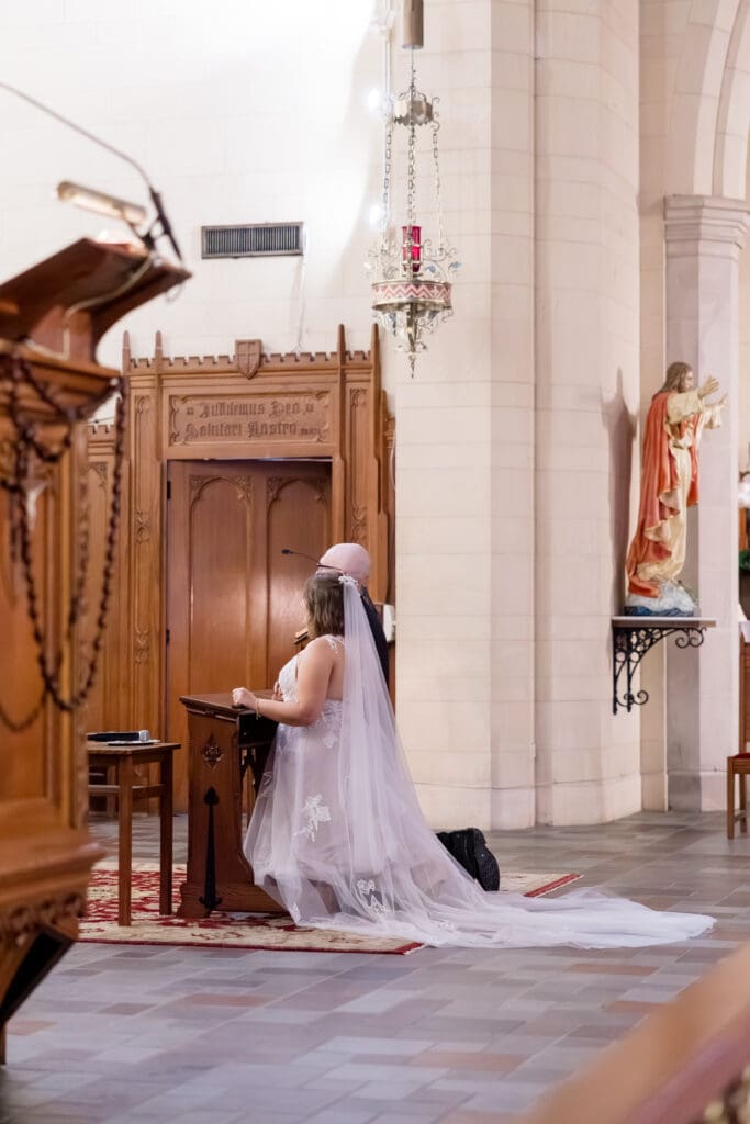 Bride and groom kneeling together at altar in Catholic wedding by Texas wedding photographer