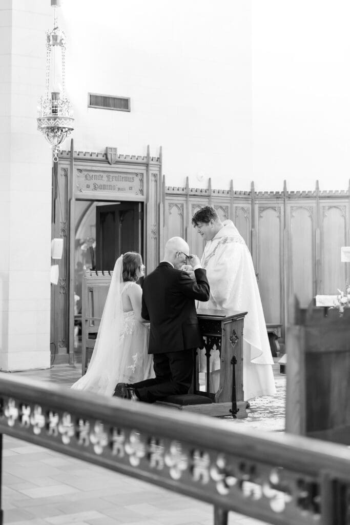 Bride and groom kneeling together at altar in Catholic wedding by Texas wedding photographer