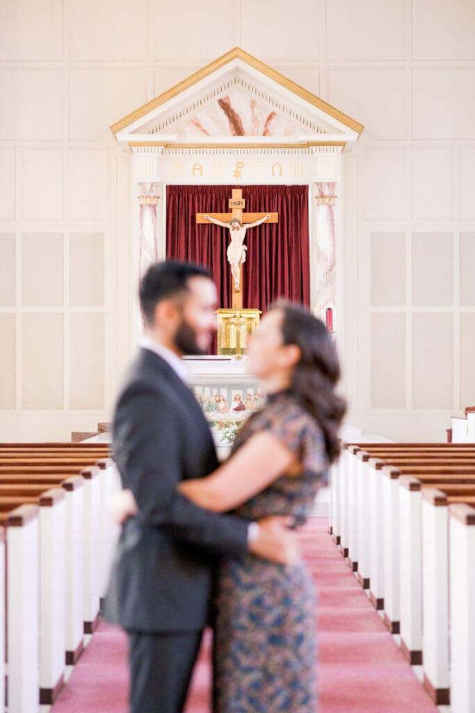 Engaged couple posing near St. Mary’s Catholic Center church entrance in College Station old church