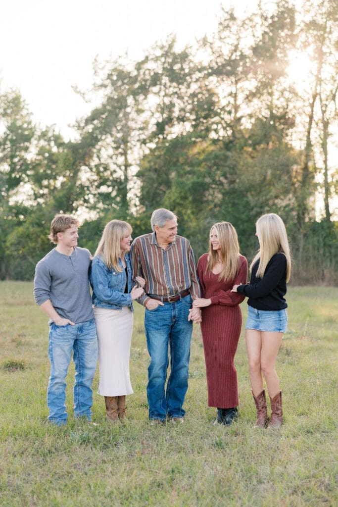Family walking through grassy field at sunset in Tomball capturing portraits