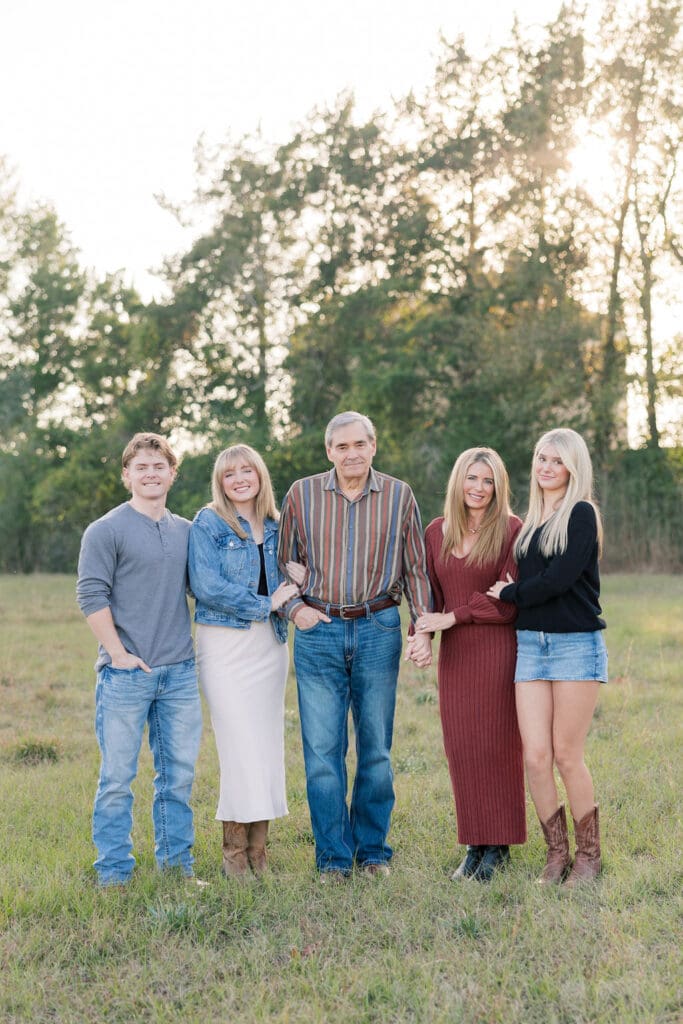 Family walking through grassy field at sunset in Tomball capturing portraits
