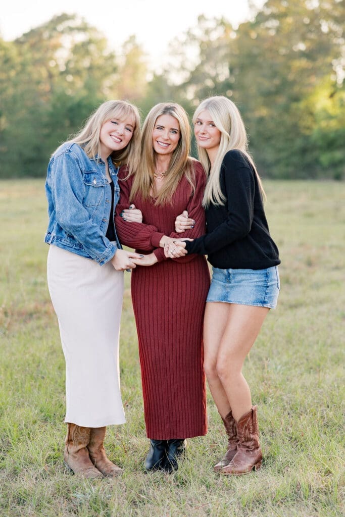 Family walking through grassy field at sunset in Tomball capturing portraits