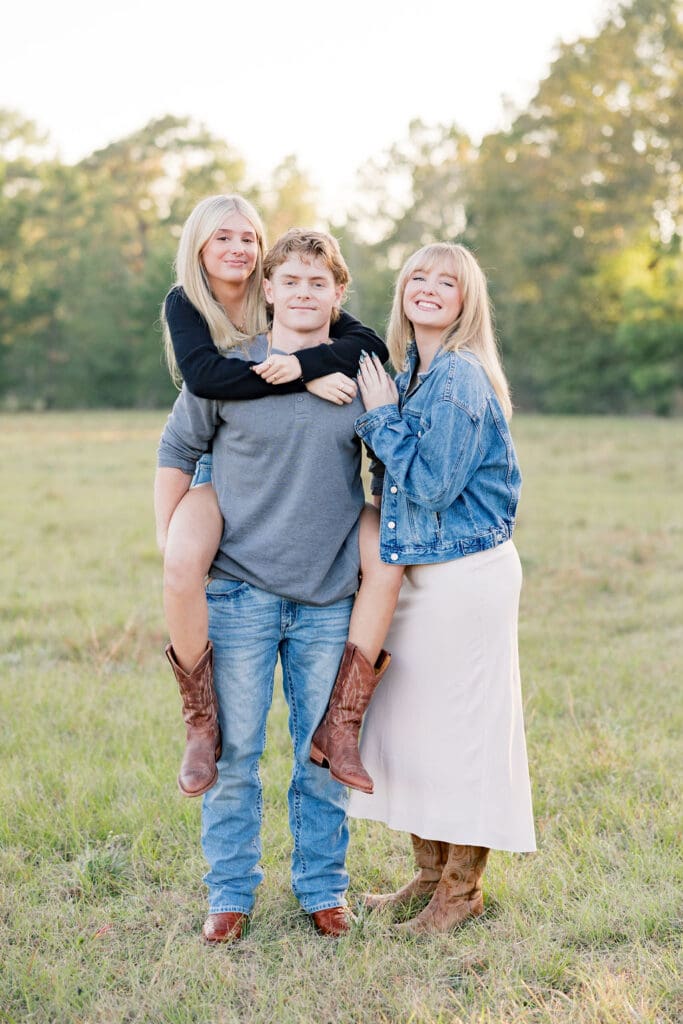 Family walking through grassy field at sunset in the woodlands capturing portraits
