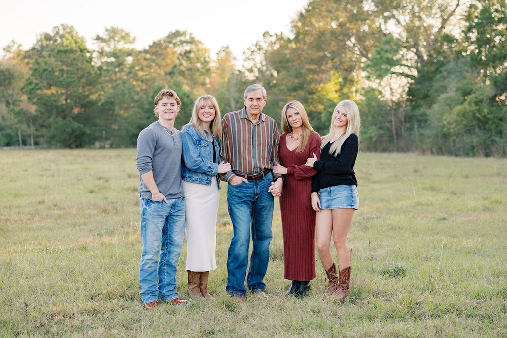 Family posing for Christmas card photos with Tomball photographer in Texas field