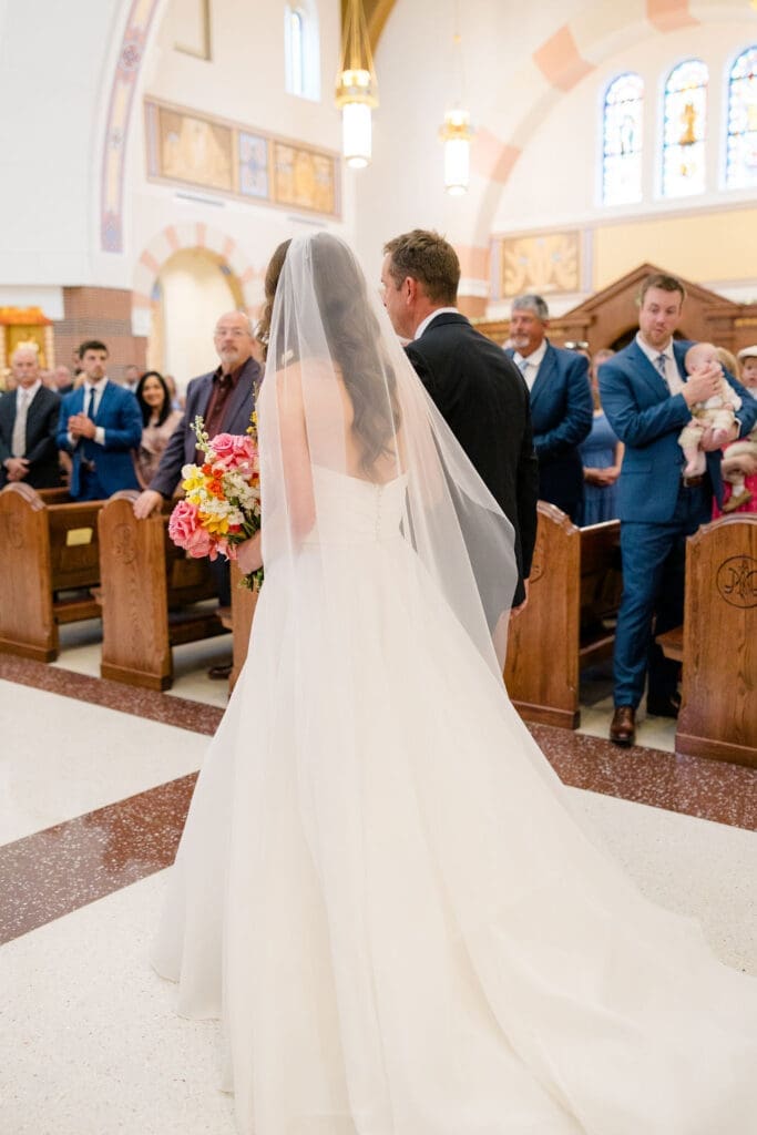 Catholic church wedding photographer Texas capturing bride walking down aisle